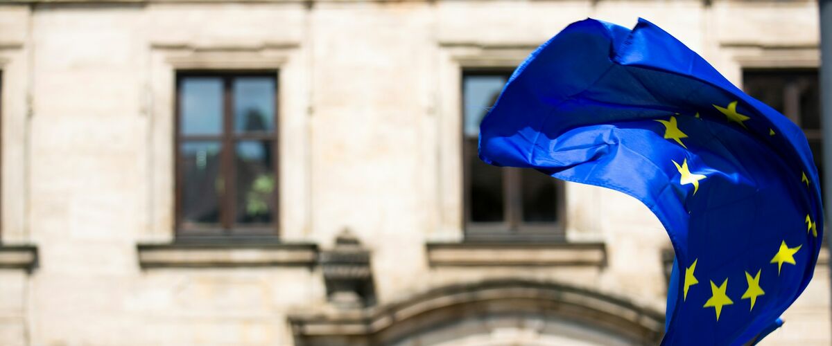 Europaflagge mit zwölf Sternen weht vor einem historischen Gebäude