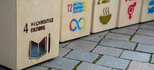 Holzkisten auf Bürgersteig mit Aufdruck SDGs / Ziele für nachhaltige Entwicklung