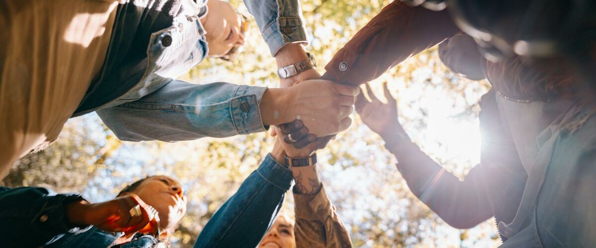 Hände von mehreren Personen, die sich in der Mitte treffen
