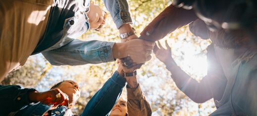 Hände von mehreren Personen, die sich in der Mitte treffen