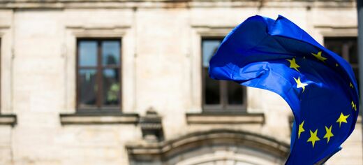 Europaflagge mit zwölf Sternen weht vor einem historischen Gebäude
