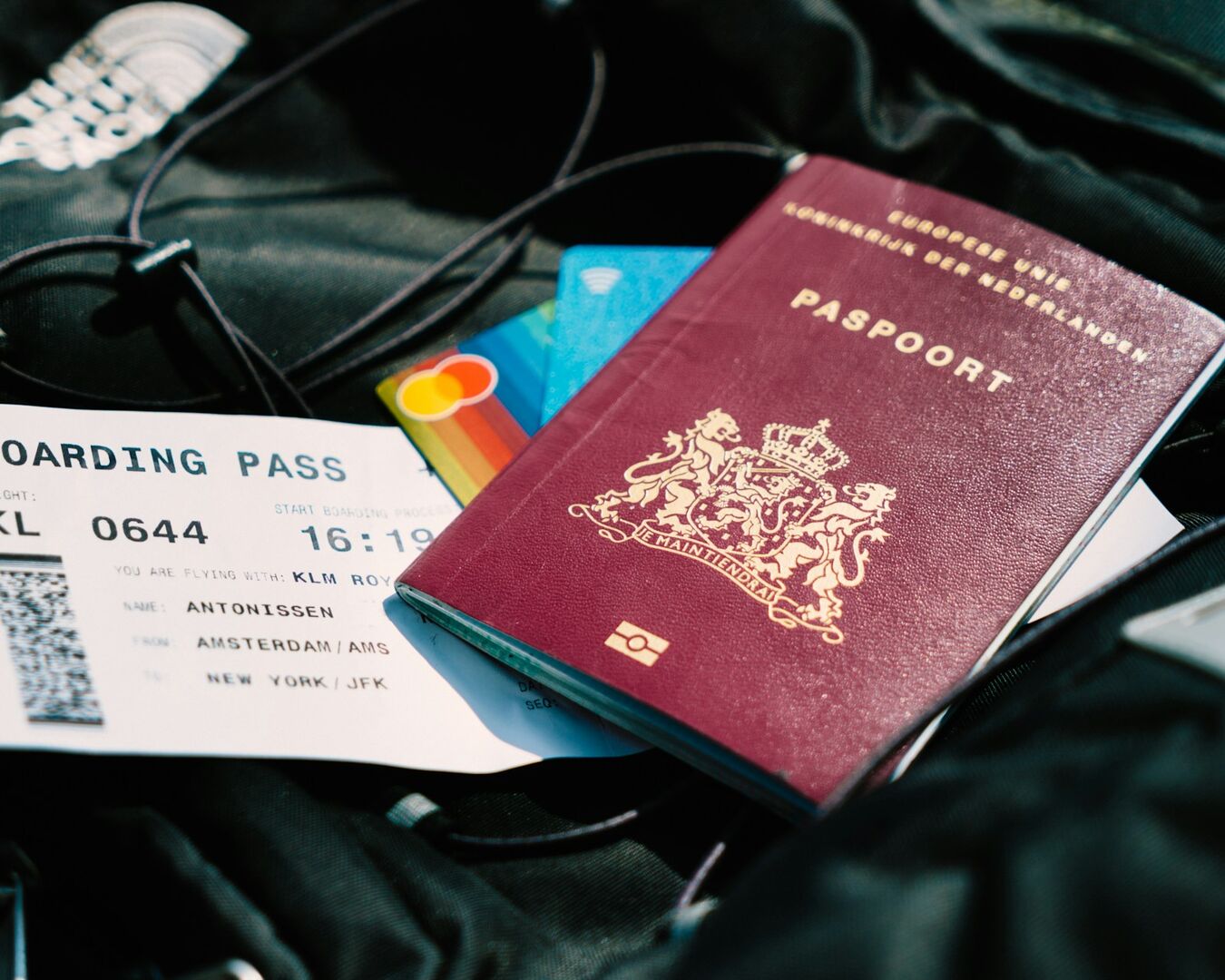 Reisepass, Boardingpass und Kreditkarten liegen auf schwarzem Stoff